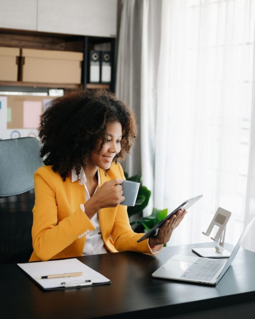 African woman using tab while drinking coffee